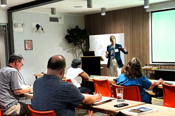 Abigail Merrill leading an AI workshop with a team seated around tables.